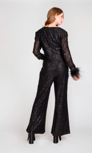 Enterito negro de lentejuelas con escote pronunciado y mangas largas con detalles de plumas.