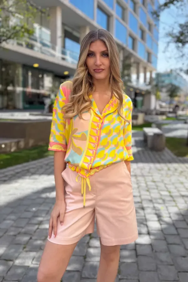 Blusa ligera en tonos amarillo y rosa con estampado geométrico, combinada con short rosa de tiro medio - Carola Pino Boutique